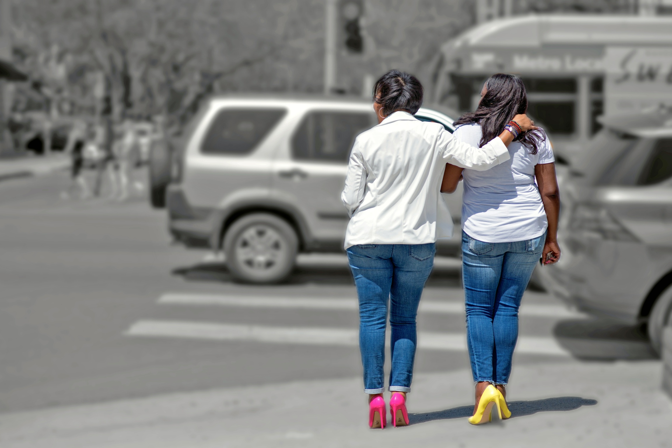 Two girlfriends walking arm in arm, wearing pink and yellow heels